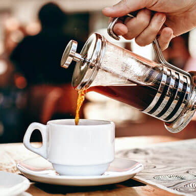 coffee being poured into mug from french press